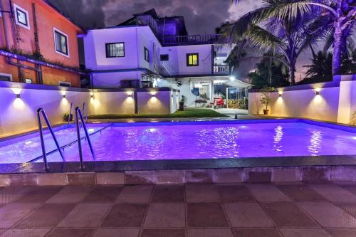 a swimming pool in front of a house at night at Antonio's hotel in Calangute