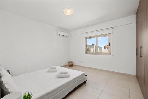 a white room with a bed and a window at Downtown Sea View Penthouse in Larnaca