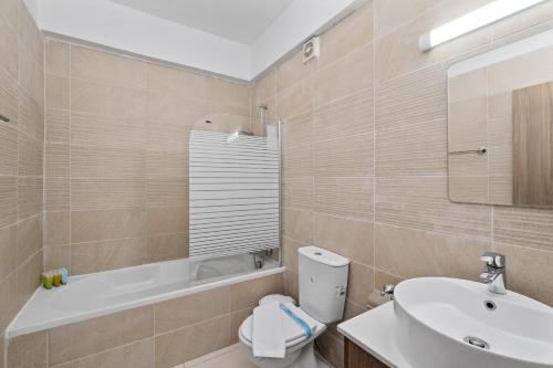 a bathroom with a sink and a toilet and a tub at Downtown Sea View Penthouse in Larnaca