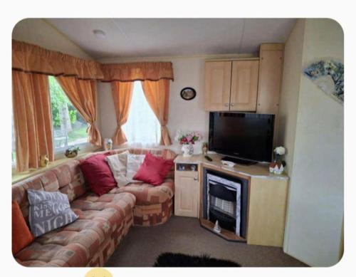 Una sala de estar con un sofá y un televisor de pantalla plana. en Cosy 8 Berth Caravan At Southview Park In Skegness Ref 33024E, en Winthorpe