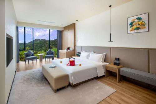 a bedroom with a large white bed and a living room at Wingate by Wyndham Emeishan Scenic Spot in Emeishan