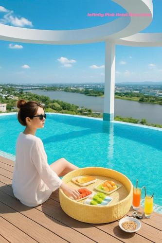 a woman sitting on a table with a tray of food at Infinity Pink Hotel Riverview in Danang