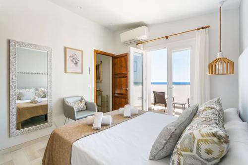 a white bedroom with a bed and a mirror at Villa Marnes by Menorca Vacations in Son Bou