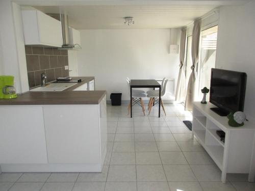 cocina con armarios blancos y suelo de baldosa en Charmant logement lumineux - Terrasse privee - Wifi, en La Chaussée-Saint-Victor