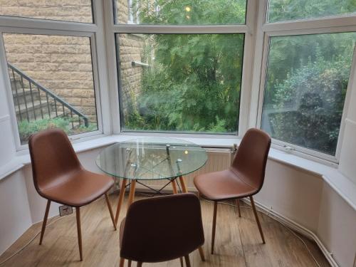 Una mesa de cristal y tres sillas en una habitación con ventanas. en Kingfield Boutique Hotel, en Nether Edge