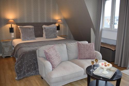 a hotel room with a bed and a couch at Le Trophée Boutique Hôtel Spa- La Loggia Appart'hôtel in Deauville