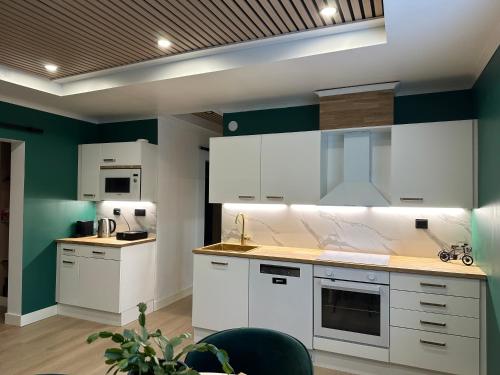 una cocina con armarios blancos y paredes verdes en Hidden gem near Fiskars and Billnäs, en Raseborg
