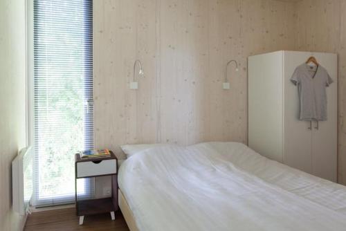 Sint MaartensvlotbrugにあるDesign Cabin Sint Maartenszeeのベッドルーム1室(白いベッド1台、ドレッサー、ドレッサー付)
