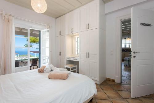 a white bedroom with a bed and a view of the ocean at Thea Estate in Kelliá