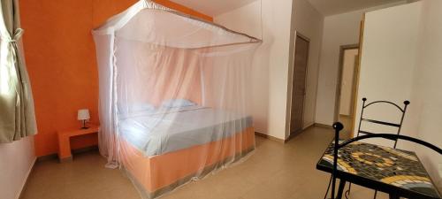 a bedroom with a canopy bed and a chair at Villa Saraba in Somone