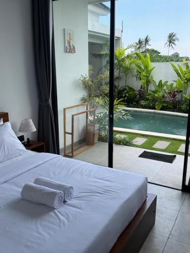 a bedroom with a bed and a view of a pool at Famiglie Guest House in Canggu