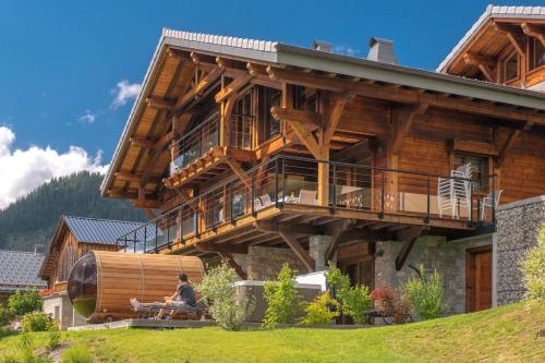 a large wooden house with people sitting in front of it at Chalet Familial Spacieux Le Spencer Grand Luxe Châtel in Châtel