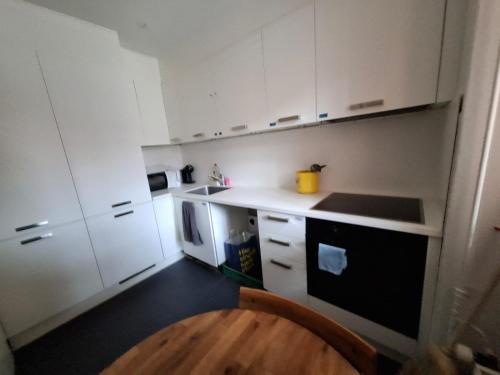 a small kitchen with white cabinets and a wooden floor at My Room Luzern in Luzern