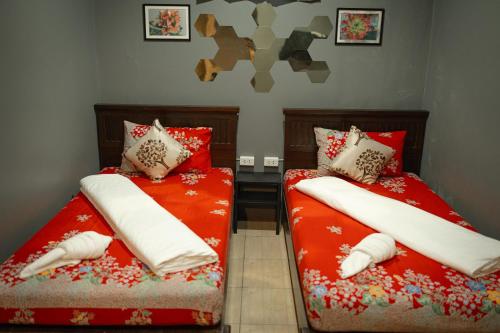 two beds in a room with red sheets and pillows at Baan Paea Guest House in Ban Ket Ho