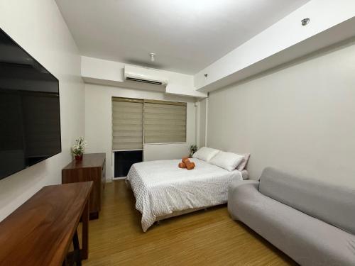 a bedroom with a bed and a couch and a television at Apad@graceresidences nr BGC in Manila