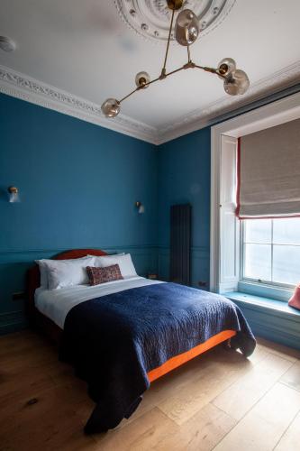 a bedroom with a blue wall with a bed at Lido Townhouse in Bristol