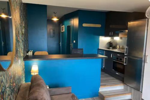 a kitchen with blue walls and a couch in a room at Une escapade à l'estacade in Deauville