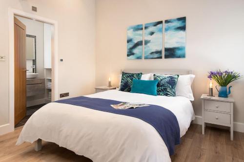 a bedroom with a large white bed with blue pillows at The Smithy at West Lyham in Chatton