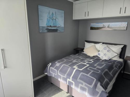 a bedroom with a bed and a sailboat on the wall at Elegantes Meerblick-Apartment in Hansaland