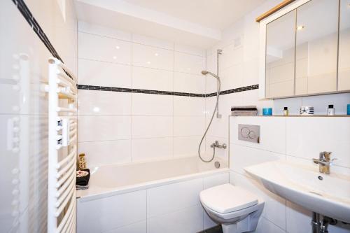 a white bathroom with a sink and a tub and a toilet at Elegantes Meerblick-Apartment in Hansaland