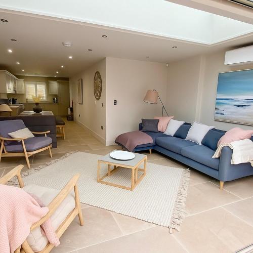 a living room with a blue couch and a table at Boutique Burnham Market Cottage in Burnham Market