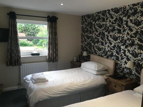 1 dormitorio con 2 camas y ventana en The Half Moon, en Petersfield