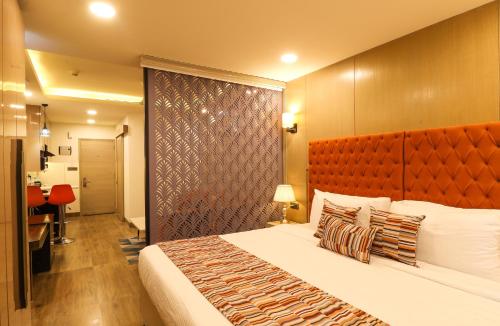 a bedroom with a large bed with a orange headboard at AR Suites Sohna Road in Gurgaon