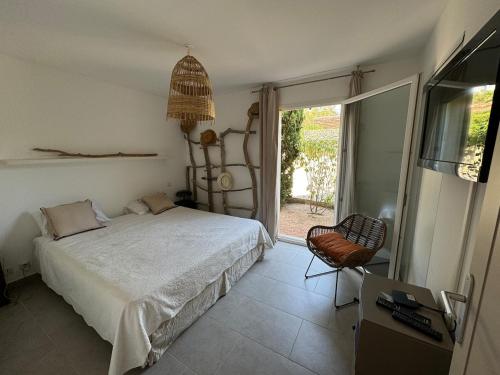 a bedroom with a bed and a chair and a window at Pinarello - Les hameaux 1 in Sainte-Lucie de Porto-Vecchio