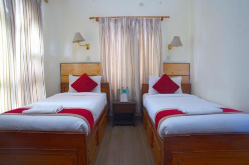 ein Schlafzimmer mit zwei Betten mit roten Kissen in der Unterkunft Hotel Lake Place in Pokhara