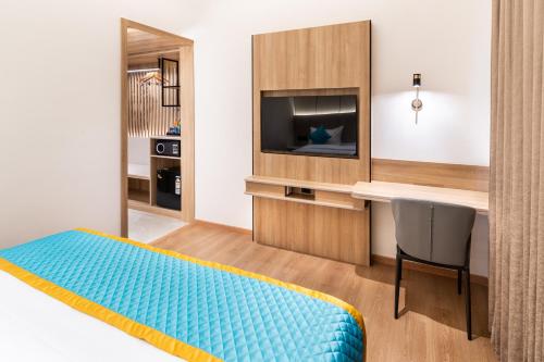 a bedroom with a bed and a desk and a television at Hotel Lenexa by Bestinn Leisure in Bengaluru