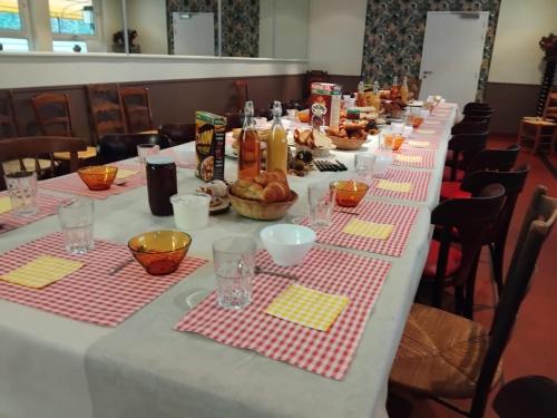 une longue table recouverte d'une nappe blanche sur laquelle est disposée de la nourriture dans l'établissement Gite Le Relais Saint Michel, à Domfront