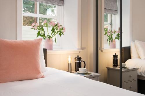 a bedroom with a bed and two windows with flowers at The Stables at West Lyham in Chatton