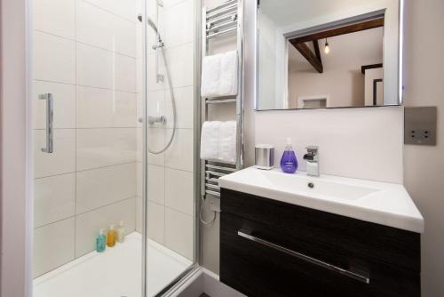 a bathroom with a sink and a shower with a mirror at The Stables at West Lyham in Chatton