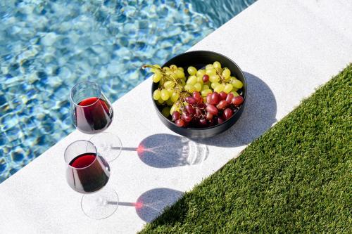 a bowl of grapes and wine glasses next to a pool at Golden Gaia 