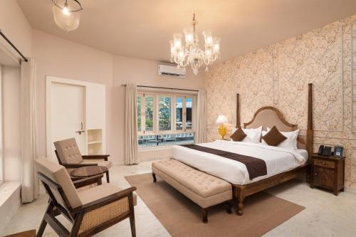 een slaapkamer met een bed, een stoel en een kroonluchter bij Victoria Mansion - A Signature Collection by HST Hotels, Pure Vegetarian in Udaipur