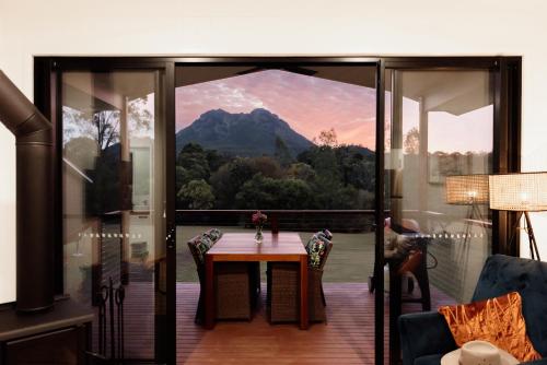 ein Zimmer mit Tisch und Blick auf einen Berg in der Unterkunft Tuckeroo Cottages - Cockatoo Cottage in Bigriggan