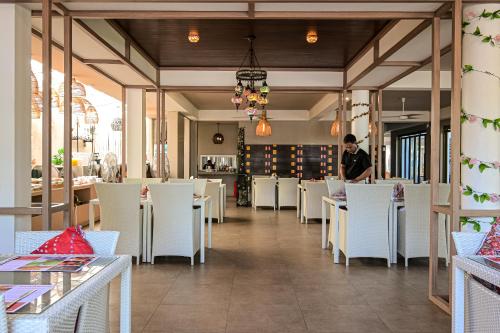 a man standing in a restaurant with white tables and chairs at Ramada by Wyndham Phuket Southsea in Karon Beach