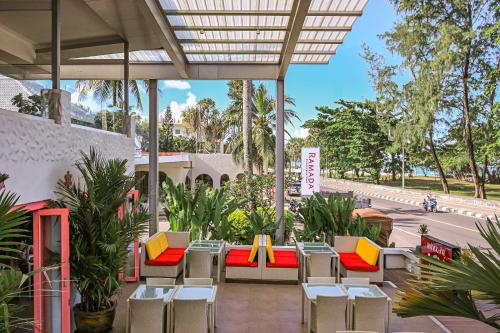 a patio with tables and chairs and palm trees at Ramada by Wyndham Phuket Southsea in Karon Beach
