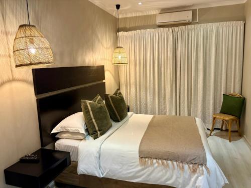 a bedroom with a large bed and a window at The Suburban Guest House in Bloemfontein