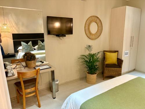 a bedroom with a bed and a desk with a mirror at The Suburban Guest House in Bloemfontein