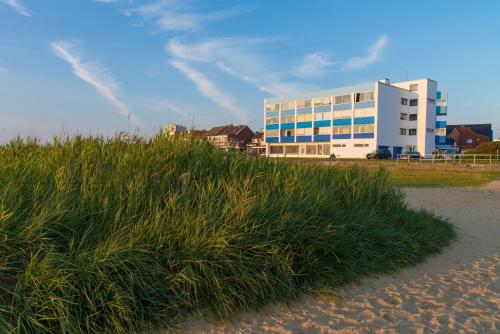 a building on the beach next to a field of grass at Haus Seehund in Cuxhaven