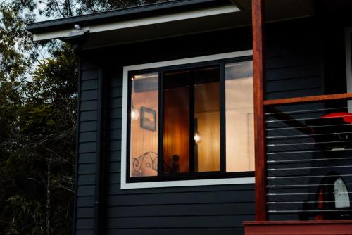 ein Fenster an der Seite eines schwarzen Hauses in der Unterkunft Tuckeroo Cottages - Rosella Cottage in Maroon