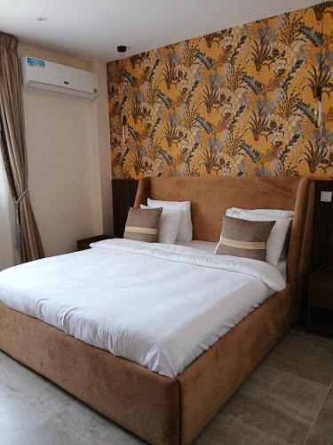 Una cama grande en un dormitorio con papel pintado floral. en Linaa, en Libreville
