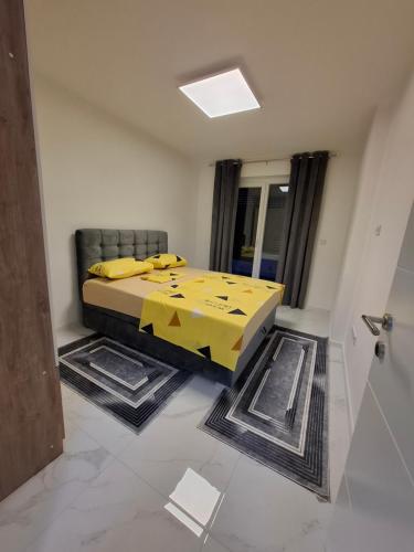 a room with a bed with a yellow blanket on it at Apartman Ditka in Bihać