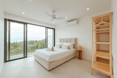 a white bedroom with a bed and large windows at Staylar Sunrise Villas - Chaweng Noi, Koh Samui in Amphoe Koh Samui