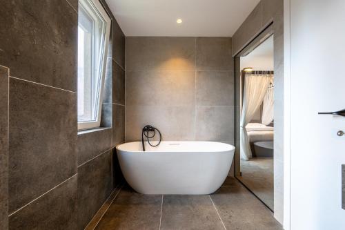 a bathroom with a white tub and a window at Five Apartments in Pristina