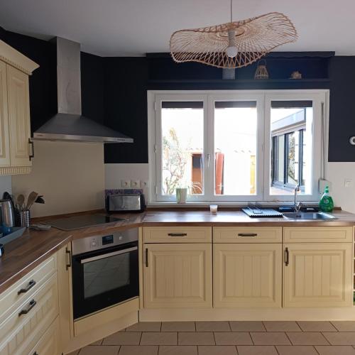 een keuken met houten kasten, een wastafel en een raam bij Les jours heureux in Gravelines