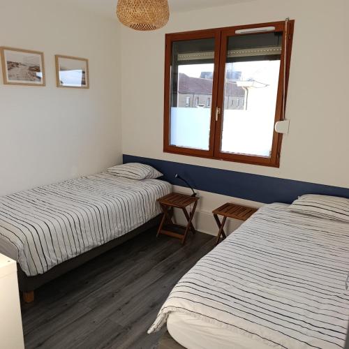 una camera da letto con due letti e una finestra di Les jours heureux a Gravelines