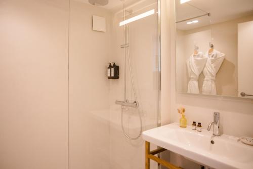 a white bathroom with a shower and a sink at Hôtel Les Hortensias du Lac in Hossegor