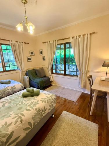 a bedroom with a bed and a desk and windows at Korla Cottage, Leura Family & Pet Friendly Stay in Leura